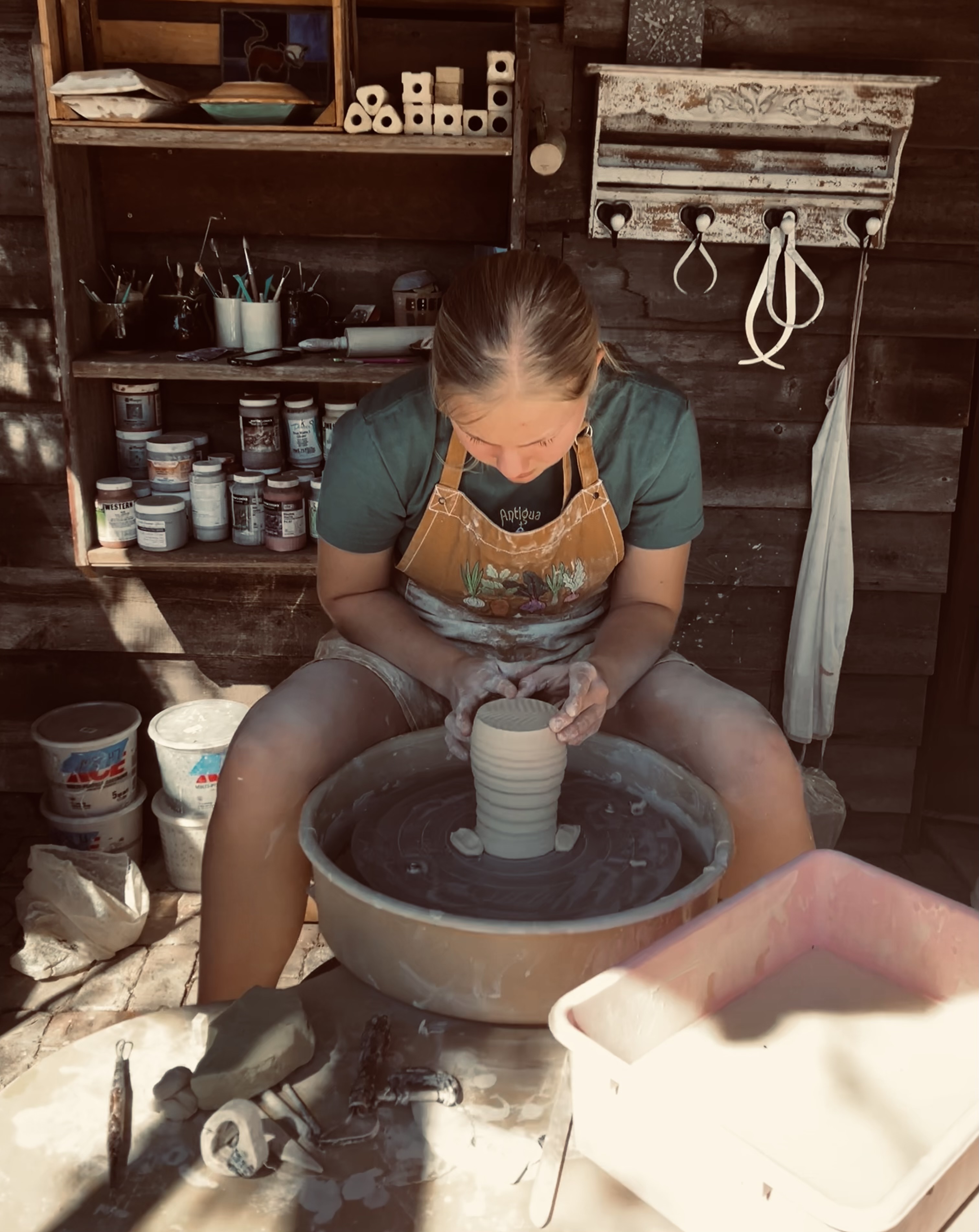 Anika shaping clay on a pottery wheel in her studio