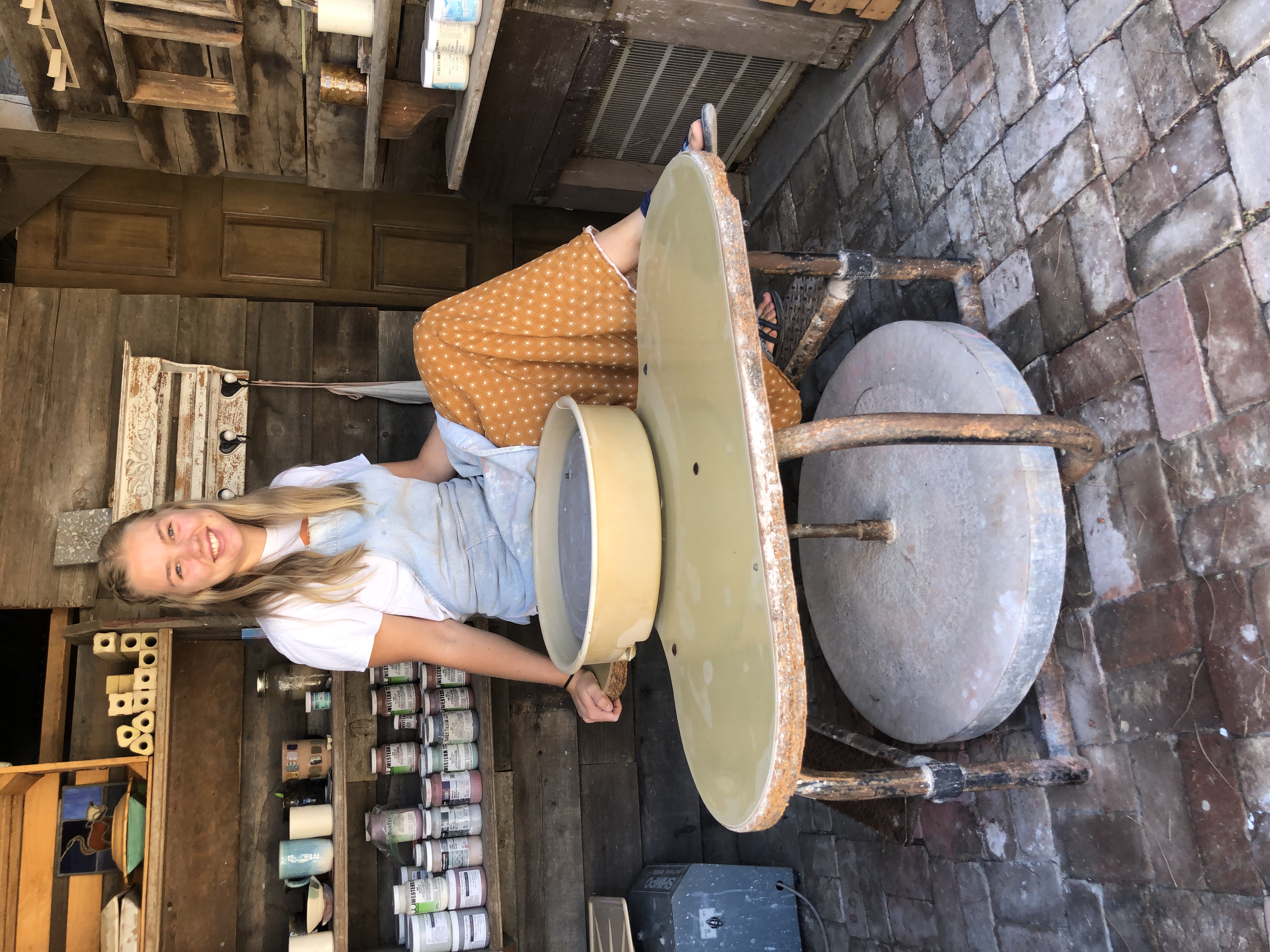 Anika sitting on her pottery wheel in her studio