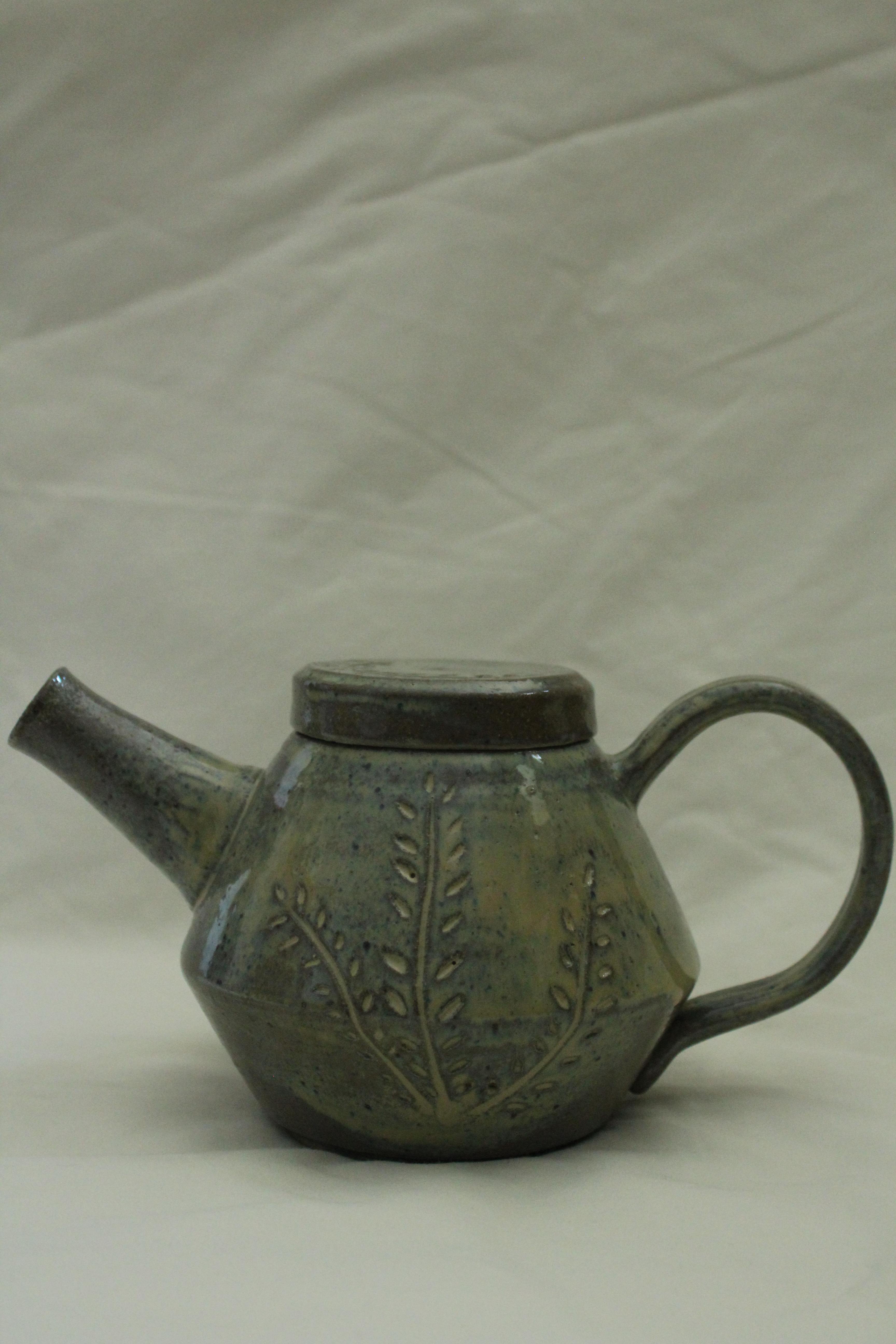 Ceramic teapot with a muted green/brown glaze and a carved leaf-like pattern